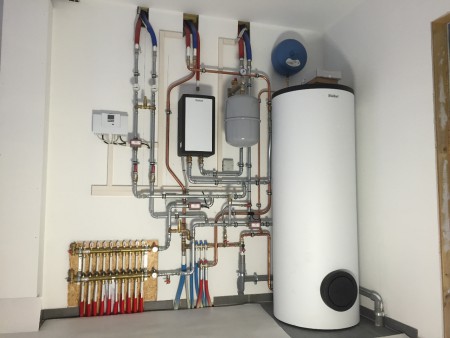 de hydraulische en elektrische aansluiting van de warmtepomp en de boiler van 300 liter in de garage